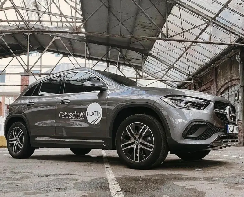 Mercedes GLA in Grau mit der Beschriftung der Fahrschule Platin in einer Halle