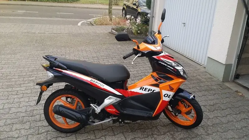 Roller in Orange und Schwarz vor einer Garage