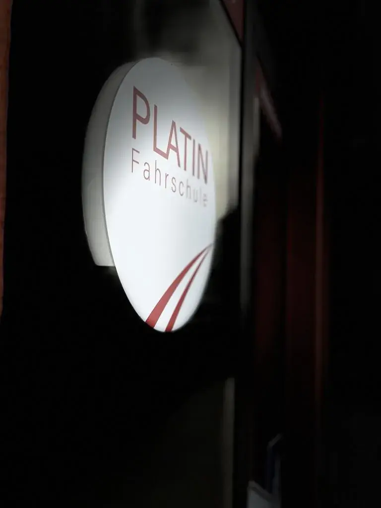 Leuchtschild der Fahrschule Platin am Eingang im Dunkeln