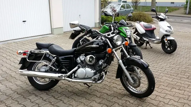 Schwarzer Chopper mit Chrom, dahinter ein weißer Roller